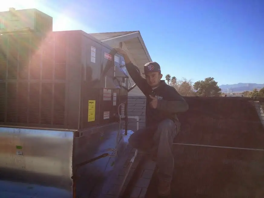 HVAC technician performing Air Duct Repair on a rooftop unit in Woburn